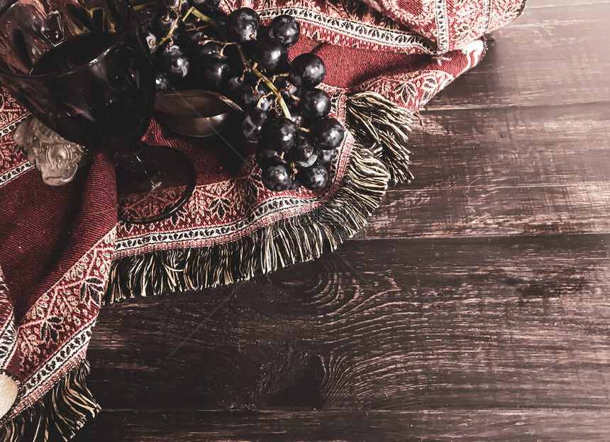 一个古老花瓶里的一帮葡萄在温暖的普什米纳背景下的木制桌子上图片
