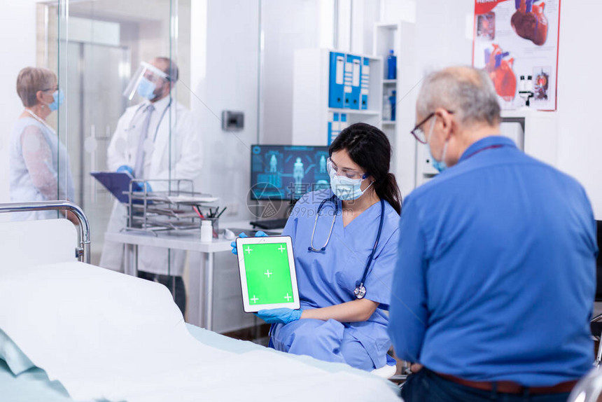 患者在医院病房咨询时看着带绿屏的平板电脑图片