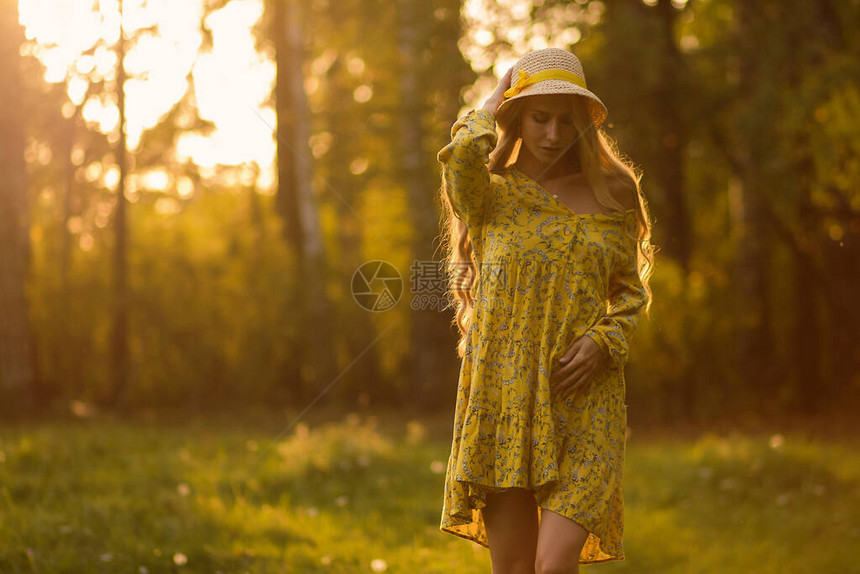 身穿鲜花裙子的金发全体金发女在森林中站立在晚上草地上时图片