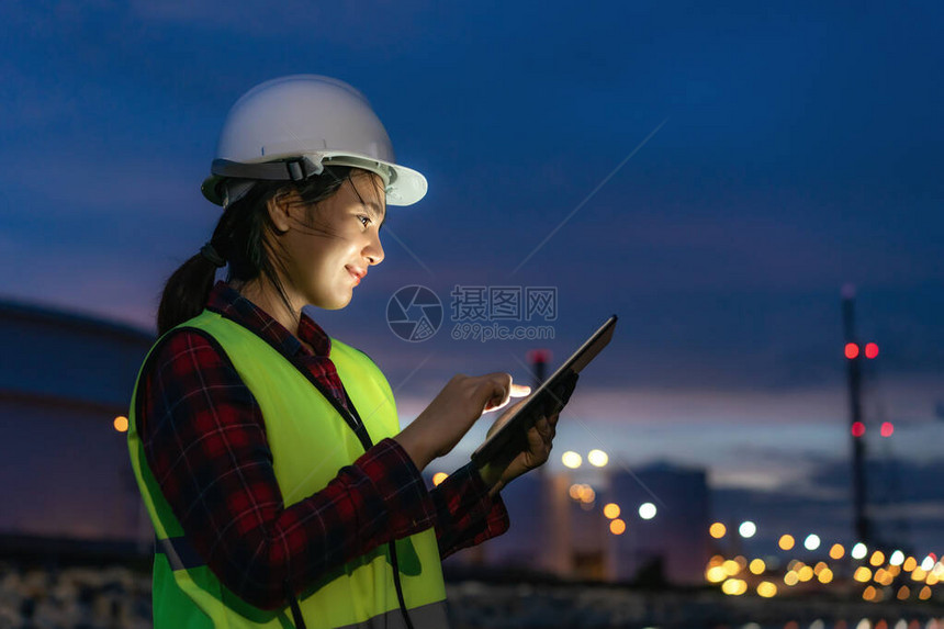 亚洲女石化工程师夜间使用数字平板电脑在石油和天然气炼油厂工业厂内进行检查员图片