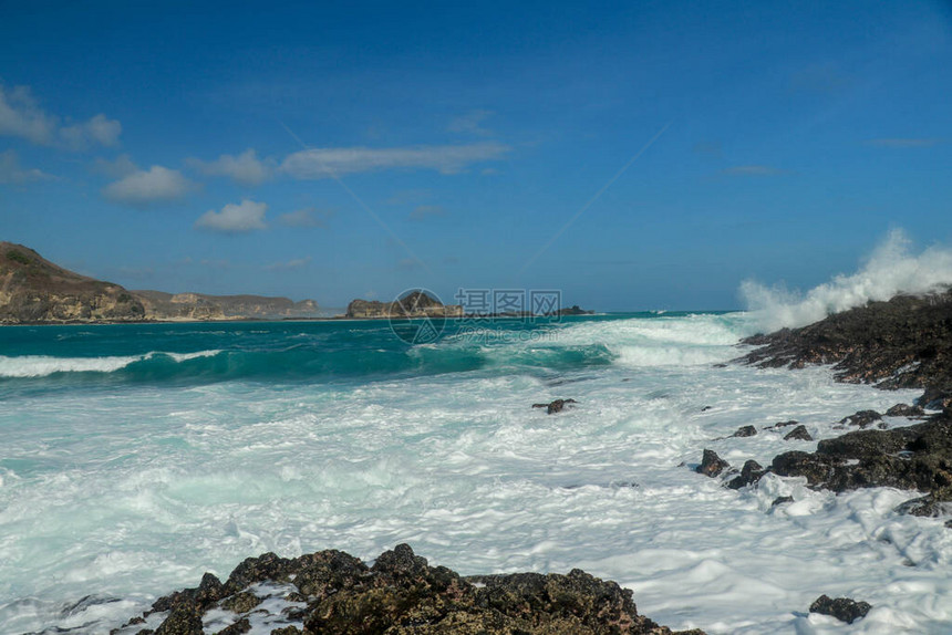 海浪在丹绒安海滩的陡峭悬崖上飞溅天堂海滩上的危险现象水从破碎的波浪的力量中冒图片
