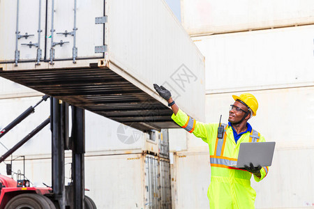 Foreman在给一个信号在港口工作将货柜移上船图片