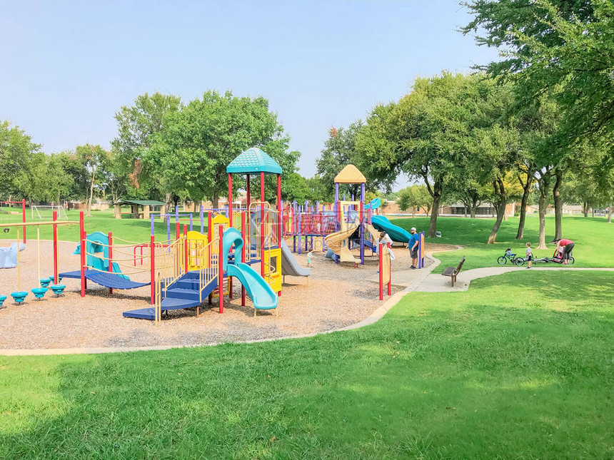 美国德克萨斯州理查森住宅区附近色彩缤纷的游乐场大橡树和绿草坪环图片