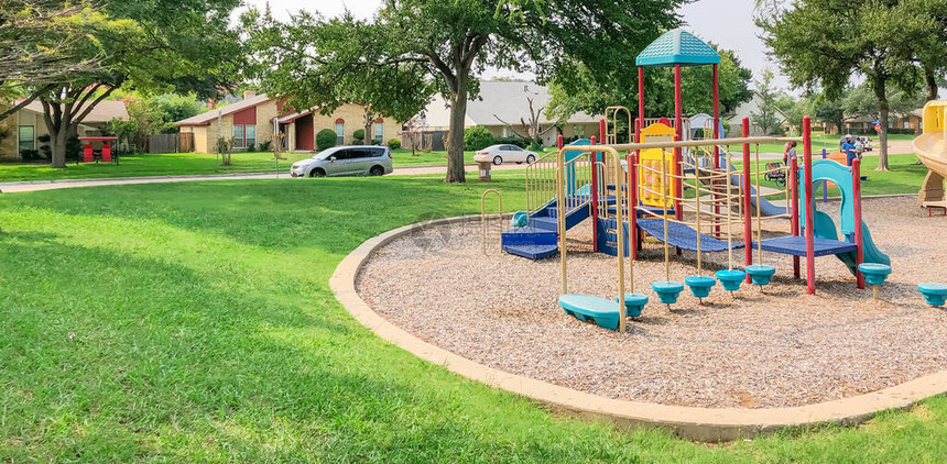 美国德克萨斯州理查森住宅区附近色彩缤纷的游乐场大橡树和绿草坪环图片