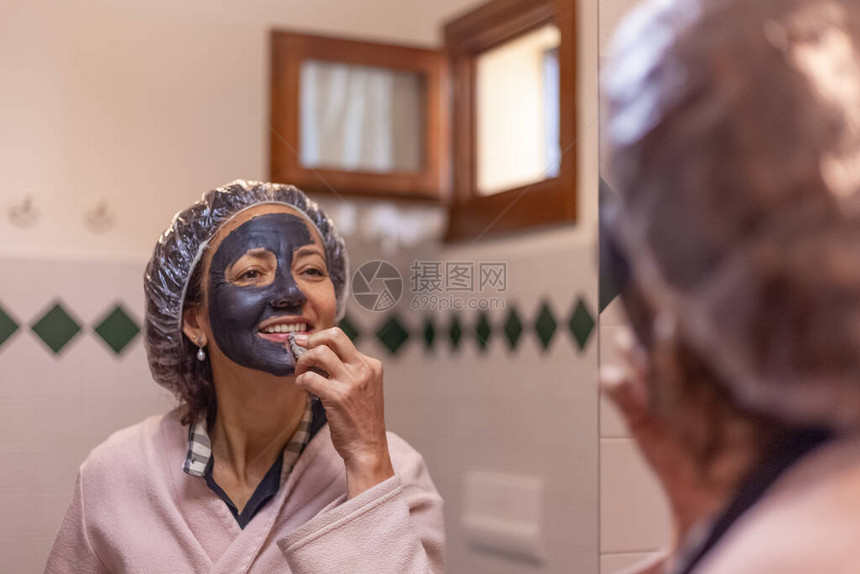 一名妇女从脸上取下泥面罩时反射镜子的近身照片图片