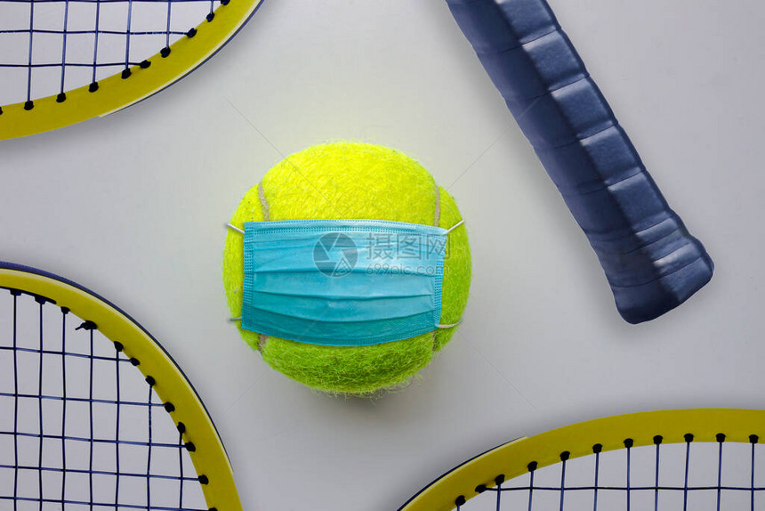 一个带面罩的网球和周围的网球拍图片