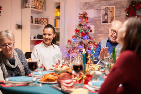快乐的女人在圣诞节的晚宴上笑得大笑餐桌上吃图片