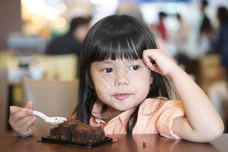 亚洲儿童可爱或小女孩快乐地吃着美味的布朗尼巧克力蛋糕图片