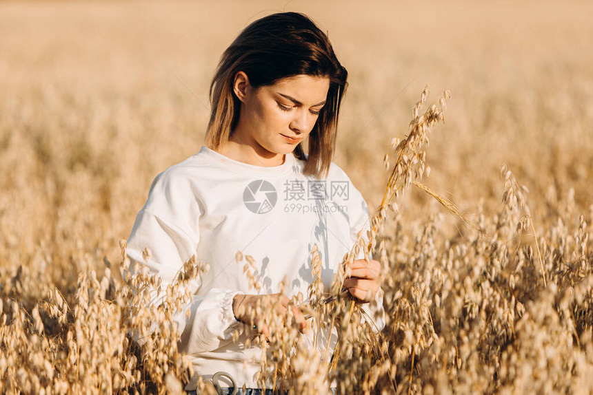 一个年轻女孩用手割了燕麦耳朵在图片