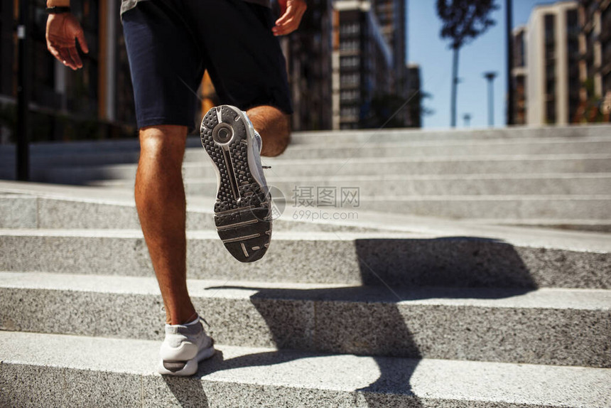 年轻人在外面锻炼运动鞋中强壮的男腿小腿和脚的背面低视图运动员慢跑或松开台阶在外面训练和锻炼图片