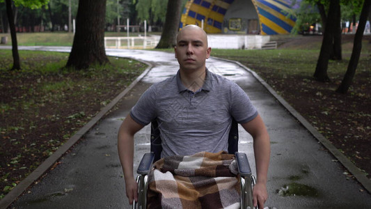 一名患有肿瘤病的年轻人骑着轮椅穿过公园高清图片