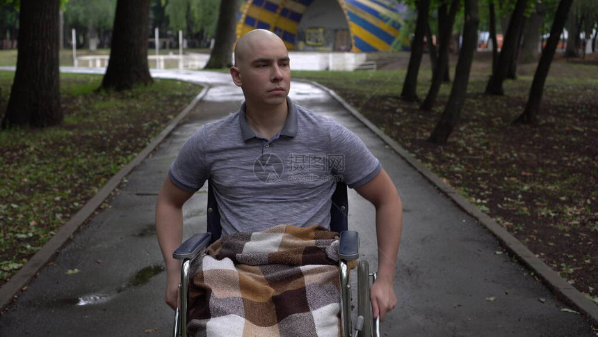 一名患有肿瘤病的年轻人骑着轮椅穿过公园图片