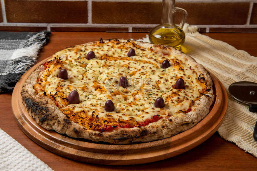 比萨鸡Catupiry风味在木板上供应由马苏里拉奶酪鸡肉奶油酪橄榄和红番茄酱制成杯橄榄油图片