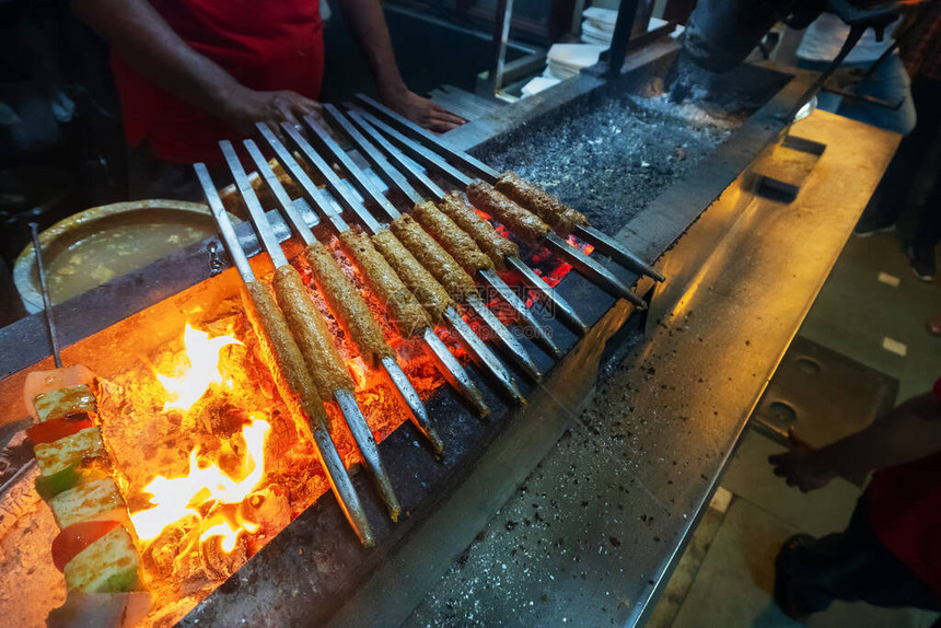 辛辣的鸡肉烤串正在用金属串烧烤图片