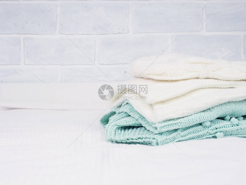 白色床上一堆温暖的针织物舒适的衣服家庭概念折叠针图片