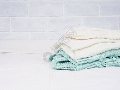 白色床上一堆温暖的针织物舒适的衣服家庭概念折叠针图片