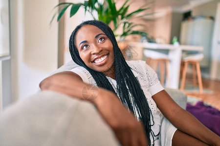 年轻非洲裔美国女人在家里坐在沙发上笑图片