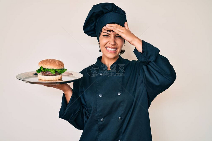 带着汉堡的美丽的黑发美女厨师长头戴手头惊讶和愤怒的脸图片
