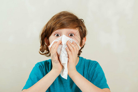 男孩流鼻涕生病的男孩坐在办公桌前孩子使用餐巾纸过敏的孩子图片