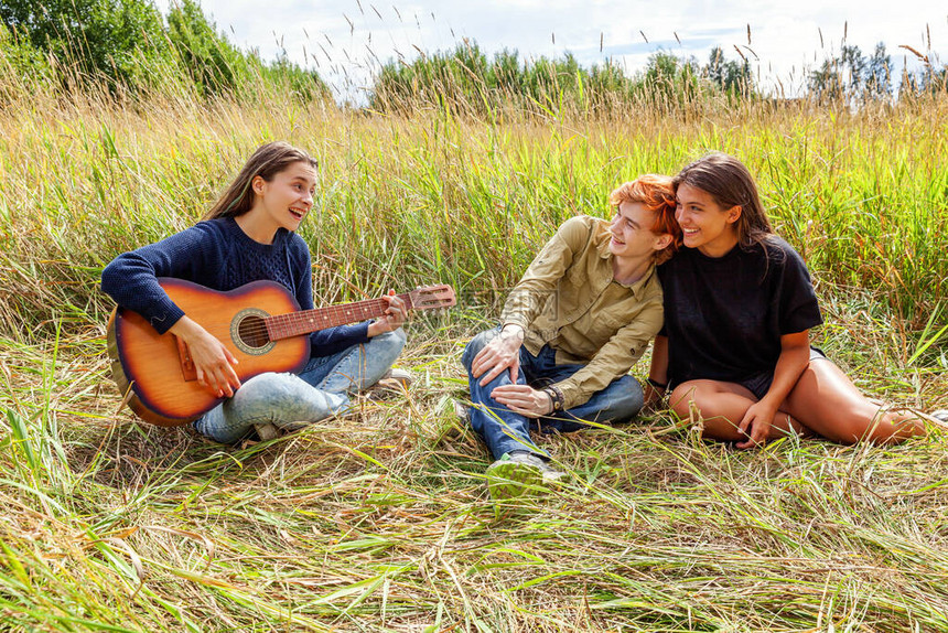 暑假期音乐快的人概念三个朋友男孩和两个女孩一起在户外玩吉他唱歌的小组与朋友在大自然中的公图片