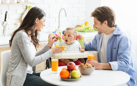 早餐时间快乐的父母在家喂小儿图片