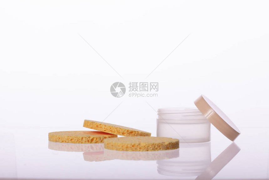 化妆品奶油罐和三个弹米色圆形海绵垫图片