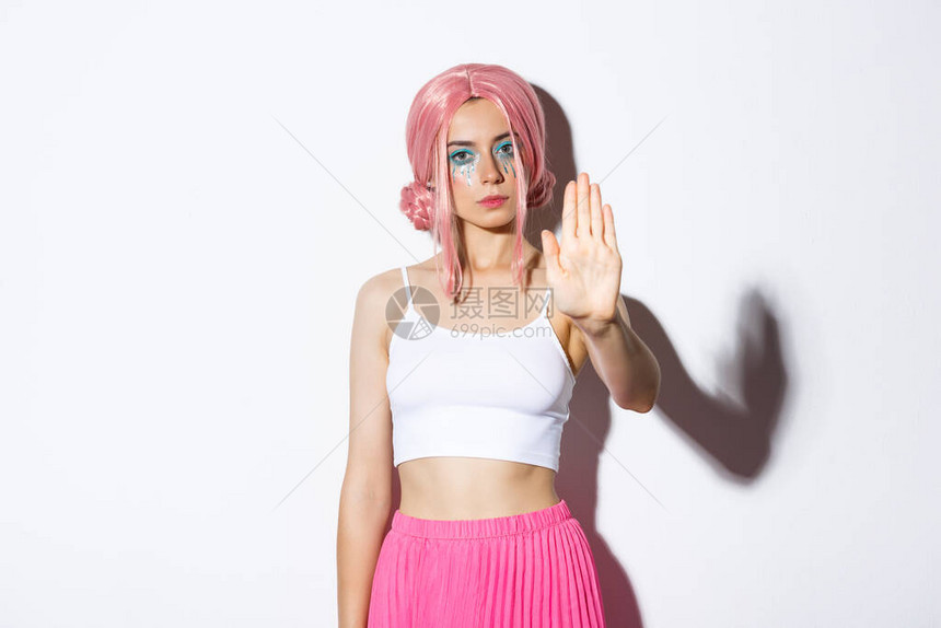 粉红色假发和圣礼服中女模特的严肃形象显示停止牌伸出手来拒绝或禁止一些不好的东西图片