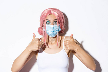 穿着粉红色假发和医用面具的兴奋可爱女孩近身露出快乐的表情图片