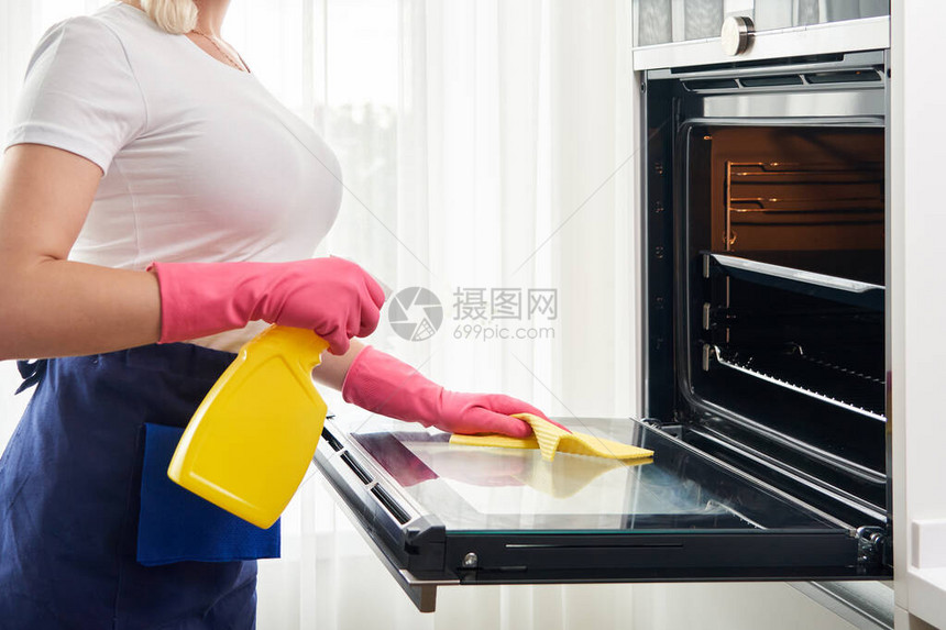 厨房的年轻女清洁炉清洁服图片
