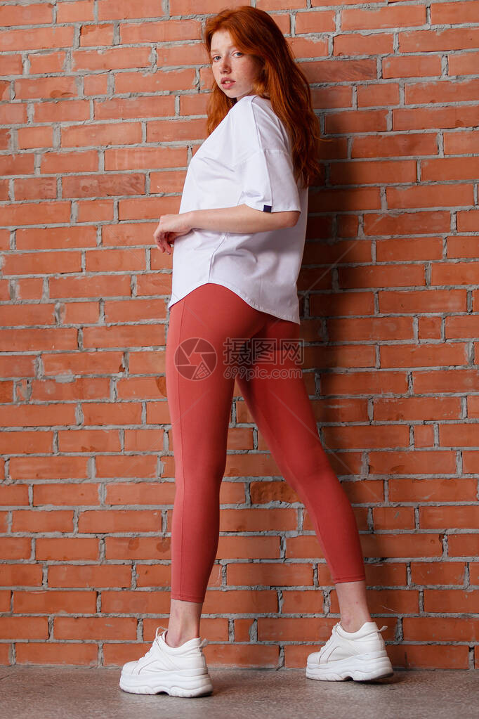 穿着短裤和白色T恤的美丽红发年轻女孩的时装风格工作室肖像图片