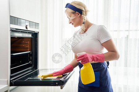 厨房的年轻女清洁炉清洁服图片