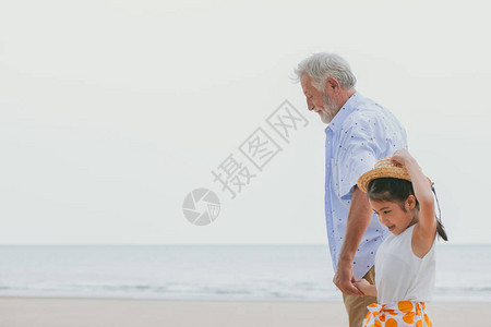 长者与孙子一起在海边露天散步图片