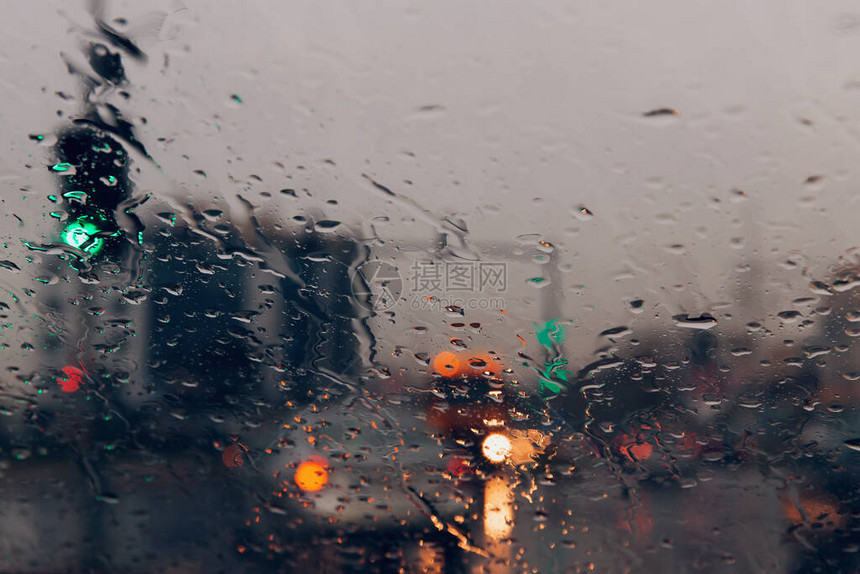 通过汽车挡风玻璃上的雨滴看到城市道路图片