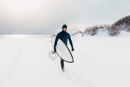 冬天和冲浪者有冲浪板雪沙滩上有男图片