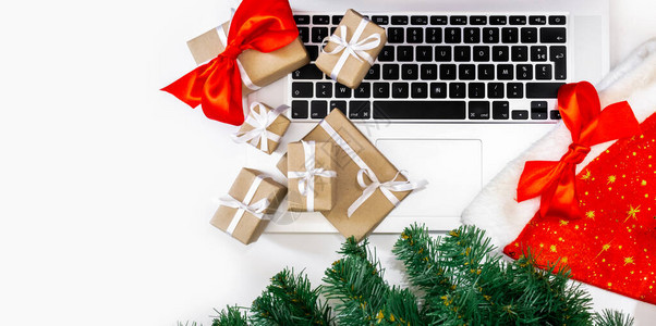 带礼物红帽子圣诞树的笔记本电脑和白色背景的包装盒图片