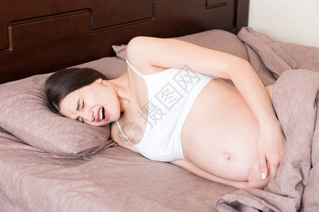 紧张的孕妇躺在床上手放在肚子上图片