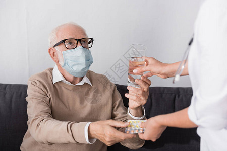 身戴医疗面具的老年男子在模糊的前景下从老年护士图片