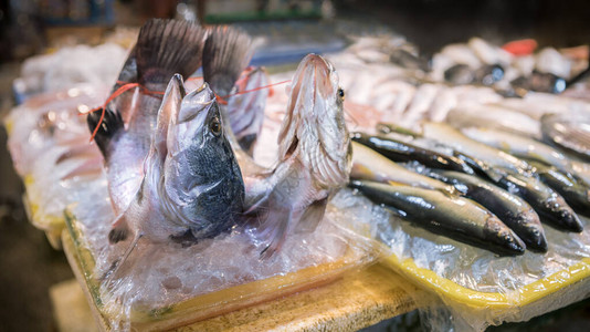 在一个可以购买许多传统食品的热门市场上出售活鱼和各种食材的摊贩在当地图片