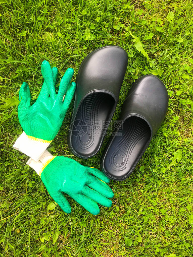 橡胶鞋和绿色建筑手套躺在绿草地上园艺工具园艺图片
