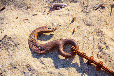 用强绳索的老化生锈的锚被放置在沙滩上图片