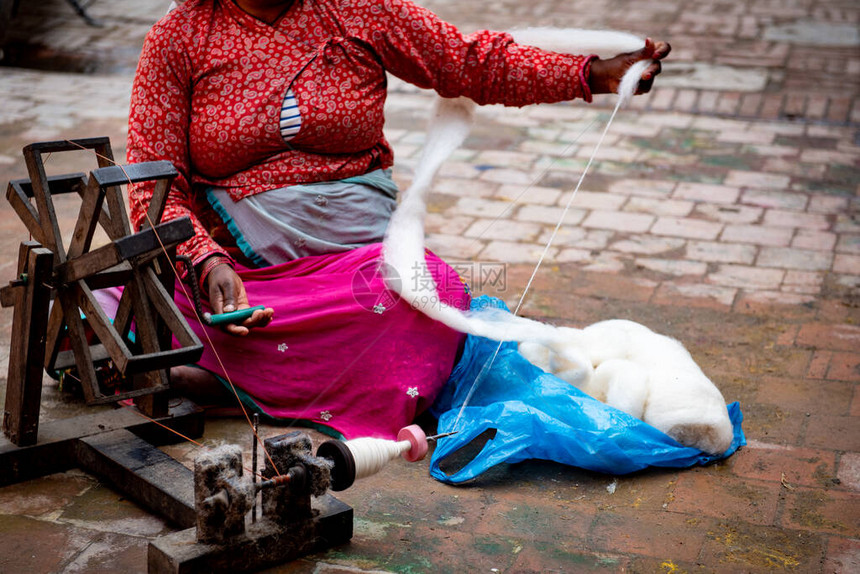尼泊尔女在木制旧机器上旋转棉线加德图片