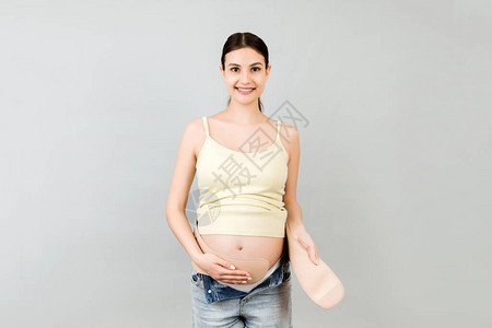 孕妇在灰色背景下穿着孕妇腰带的肖像图片
