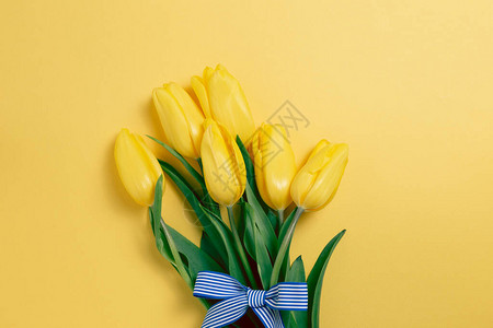 黄色的郁金香花束在黄色背景上平地顶视图图片