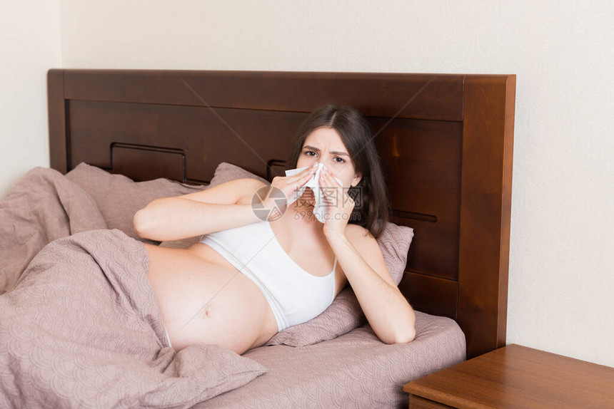 年轻不快乐的孕妇仰着枕头躺在床上图片