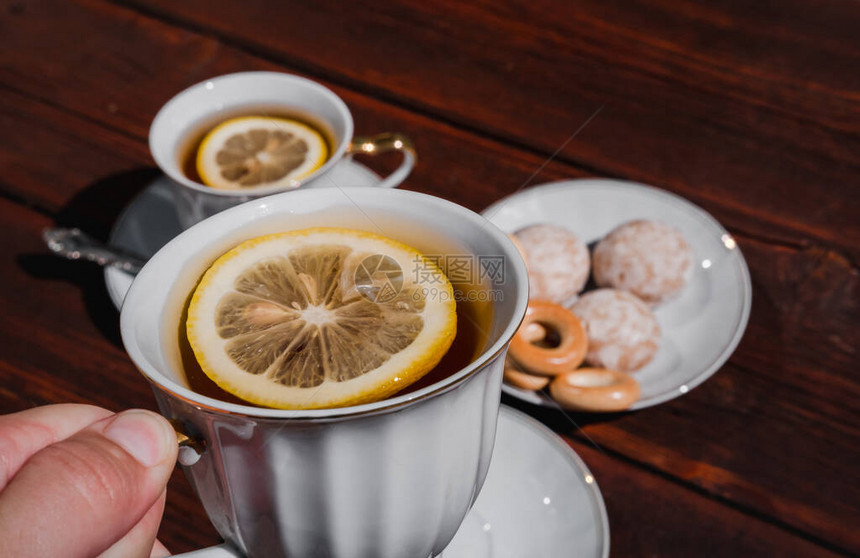 握着一杯加柠檬的茶用美味的食物和甜食开茶会图片