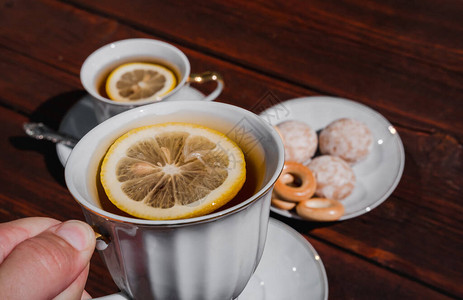 握着一杯加柠檬的茶用美味的食物和甜食开茶会图片