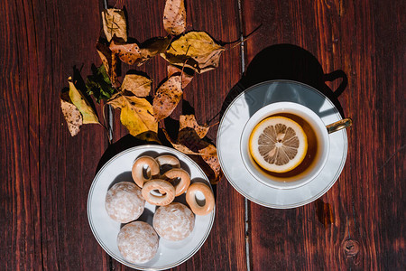 配有茶和柠檬小白碟上的茶点心和糖果秋叶和茶在图片