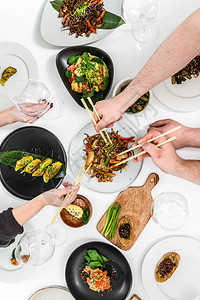 家人朋友聚餐吃春卷炒面沙拉蔬菜喝酒的人手庆祝晚宴白色图片