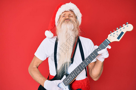 老人穿着圣诞老人服装弹着电吉他看着镜头吹着一个可爱而感的图片