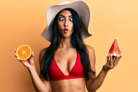 美丽的西班牙女人吃西瓜和橙子用嘴和斜眼做鱼脸疯狂图片